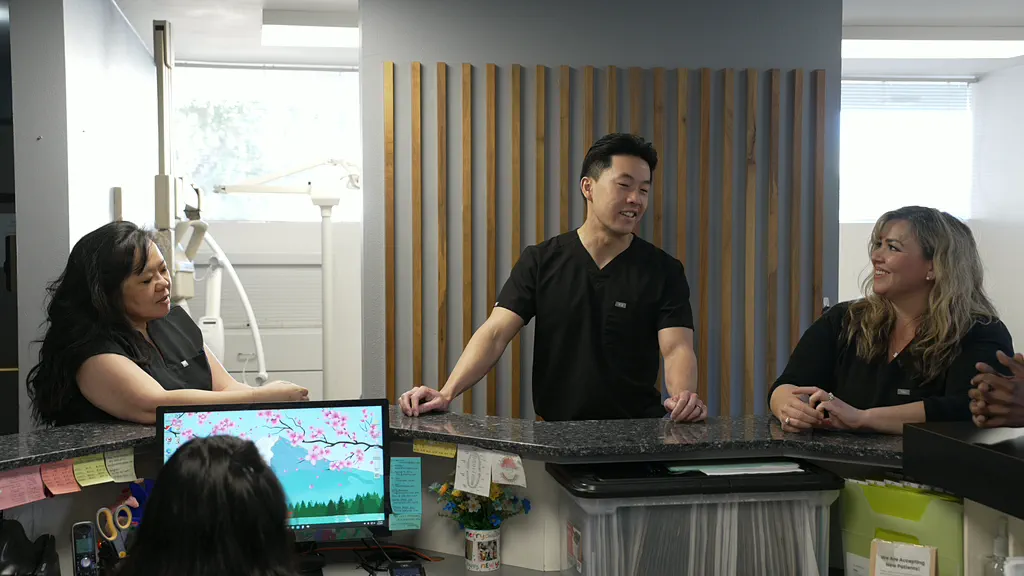 Dr. Christopher B. Wong laughing with two team members at the front desk