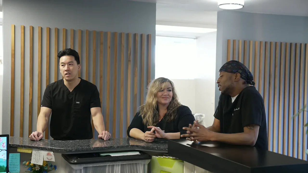 Dr. Christopher B. Wong talking with two team members at the reception counter