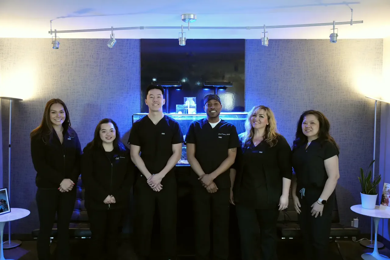 Dr. Christopher B. Wong and the dental team in the office lounge, beside the aquarium