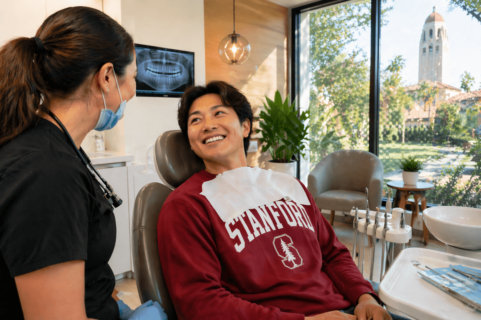 Stanford student speaking with the dental team in our Palo Alto office with Hoover Tower visible outside